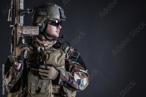 United states Marine Corps special operations command Marsoc raider with weapon. Studio shot of Marine Special Operator half-turning black background © Getmilitaryphotos