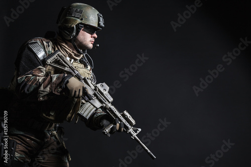 United states Marine Corps special operations command Marsoc raider with weapon. Studio shot of Marine Special Operator half-turning black background