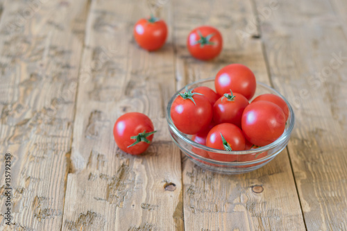 Cherry tomatoes in a bowl of glass on a rustic table.