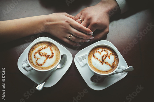 Couple in love holding hands with coffee on a table