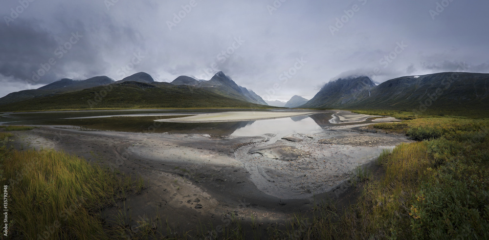 Panorama of Rapadalen river valley in dark and moody clouds land