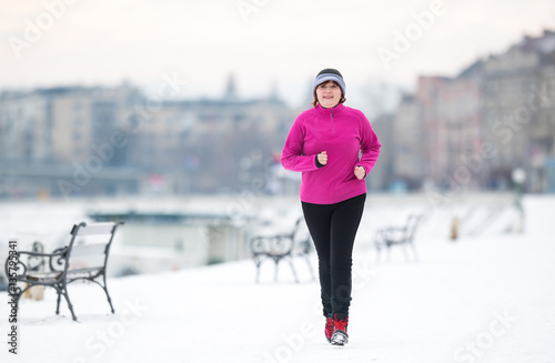 Woman wearing sportswear and running on snow during winter © Dusan Kostic