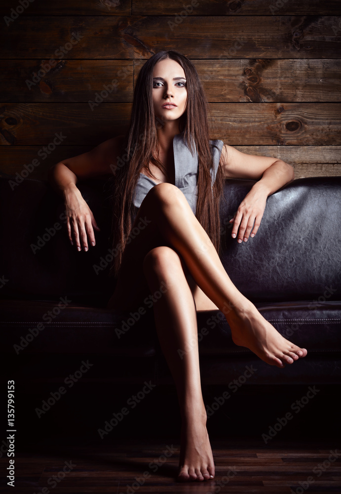 A beautiful young girl in panties and shirt sitting on sofa Stock Photo