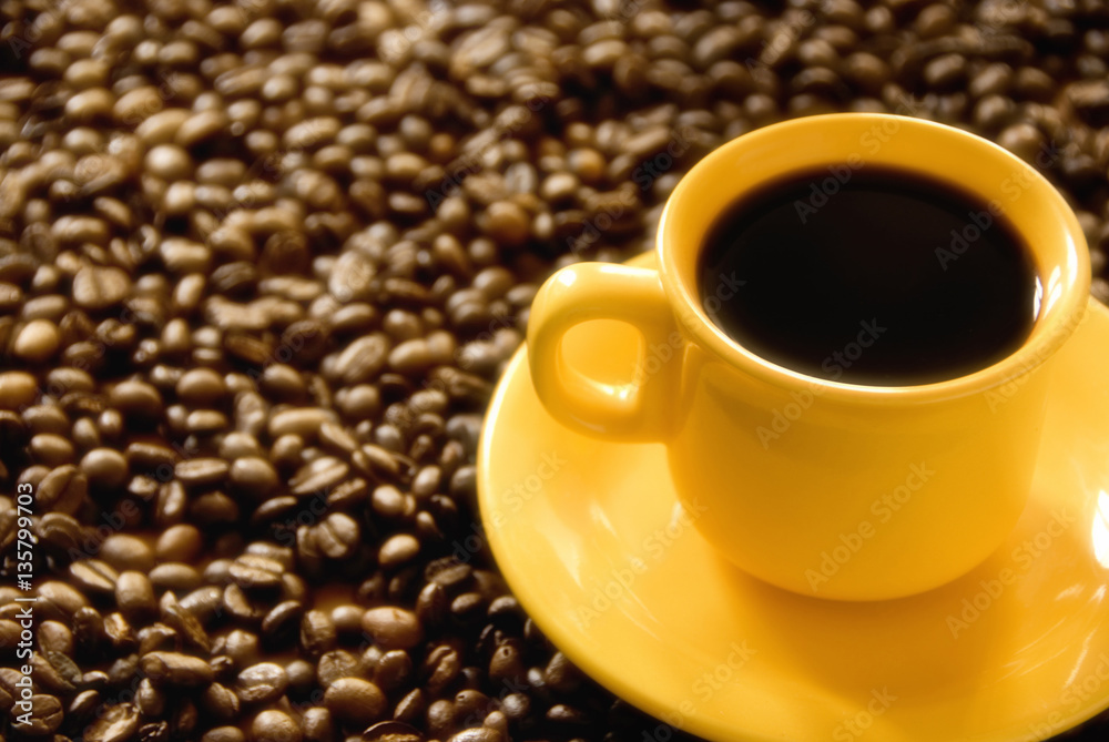 Yellow coffee cup espresso over beans background with copy space 