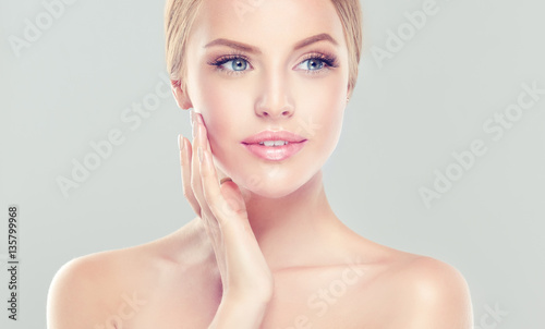 Beautiful Young Woman with clean fresh skin . Facial treatment . Cosmetology , beauty and spa . 
