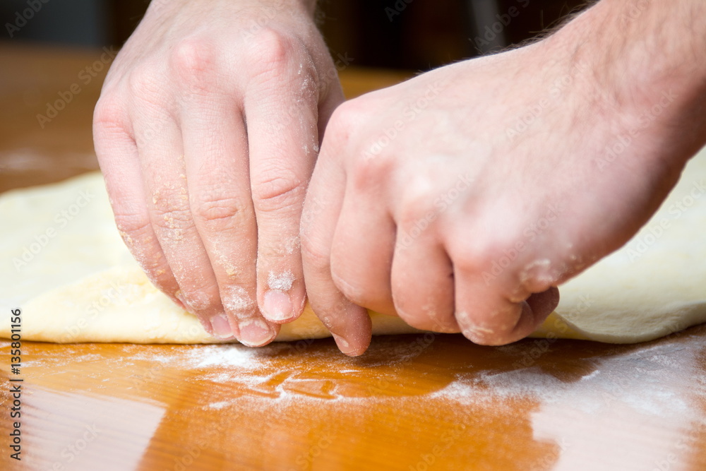 Male baker spreading dough for making pizza