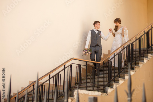 Bride and groom walking on stairs of castle after wedding ceremony