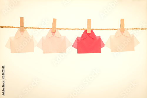 One Red among white origami shirt paper hanging  on rope © Cozine