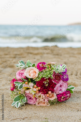 Colorful wedding bouquet from roses. Pink, red and green. Beach wedding.