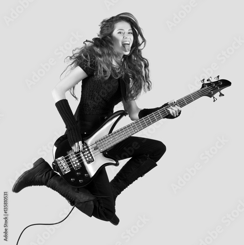 Canvas Print Beautiful girl musician and rocker jumping high in the air while playing bass gu