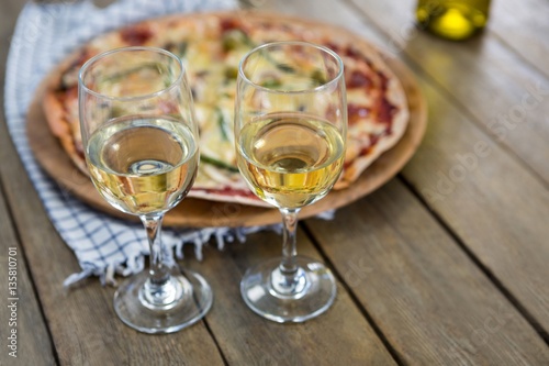 Wine glasses served with pizza in the background