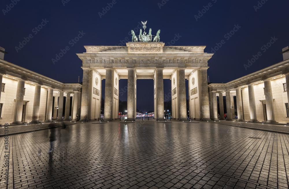 illuminated Brandenburg Gate (Brandenburger Tor) reflected on wet cobblestones at blue hour in the evening, Berlin Mitte, Germany, Europe