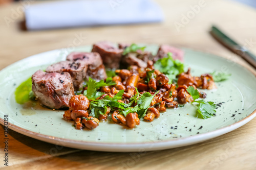 Beef tenderloin with fried chanterelles lying on a plate.