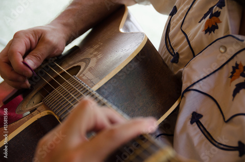 Male musician playing acoustic guitar with close up shot of hands