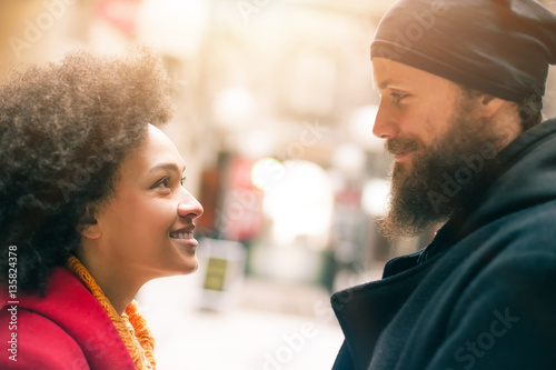 Romantic multiethnic couple in love hugging on the street