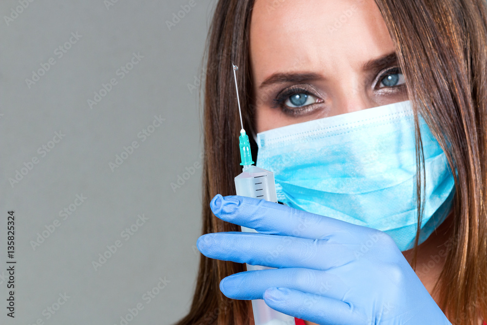 blurred Close up of female doctor standing in a robe and holding a syringe in her hand with liquid isolated on a light background
