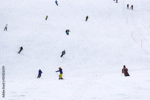 Skiers and snowboarders riding on a ski slope in Sochi mountain resort  snowy winter background