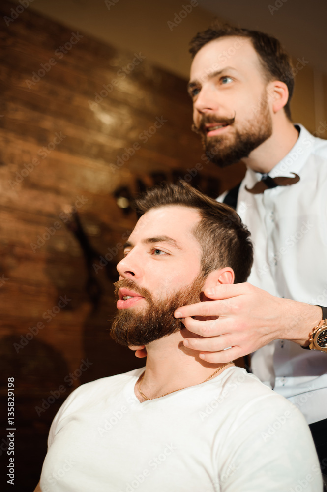 Fototapeta premium Master cuts hair and beard of men in the barbershop