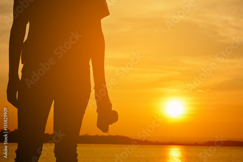 Silhouette of Asian women holding a camera shooting in nature and relax time on holiday.concept travel color of vintage tone