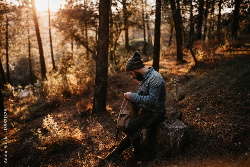Man in forest looking into backpack Man in forest looking into backpack