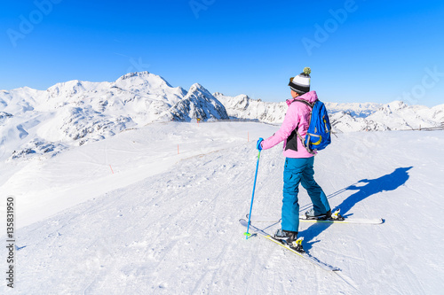 Young woman skier standing on ski slope in Obertauern winter mountain resort, Austria