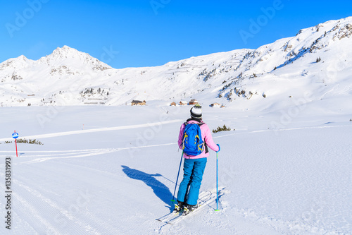 Young woman skier standing in fresh snow in Obertauern winter mountain resort, Austria
