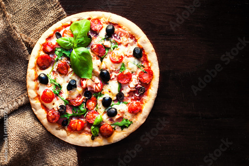 Hot pizza with Pepperoni Sausage on a dark background, top view.