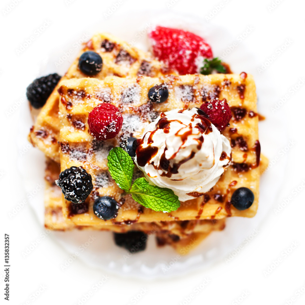 Belgian waffles with fresh berries and cream isolated on white Belgian waffles with fresh berries and cream isolated on white