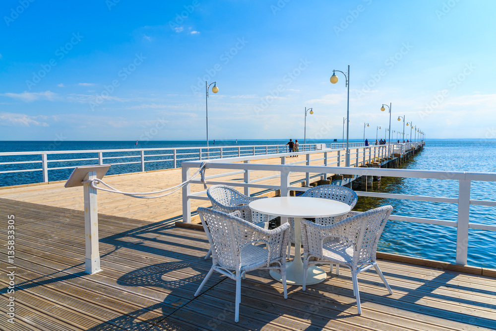 Table with chairs of cafe bar on pier in Jurata on sunny summer day, Baltic Sea, Poland
