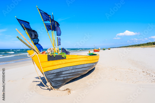 Yellow fishing boat on sandy Debki beach, Baltic Sea, Poland