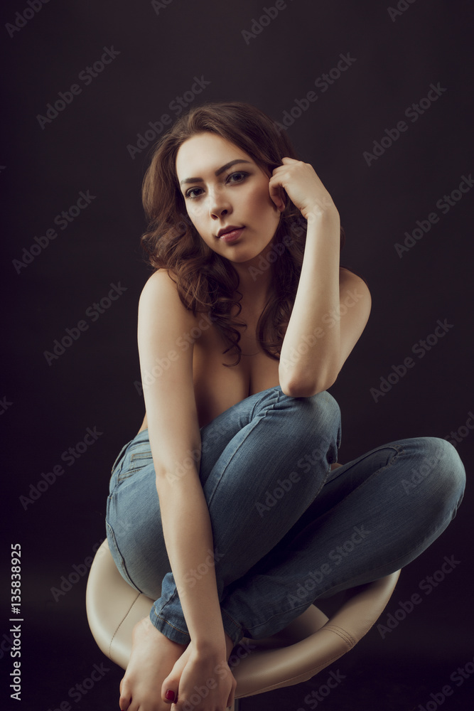 Tender brunette model in blue jeans sitting on a chair Tender brunette model in blue jeans sitting on a chair