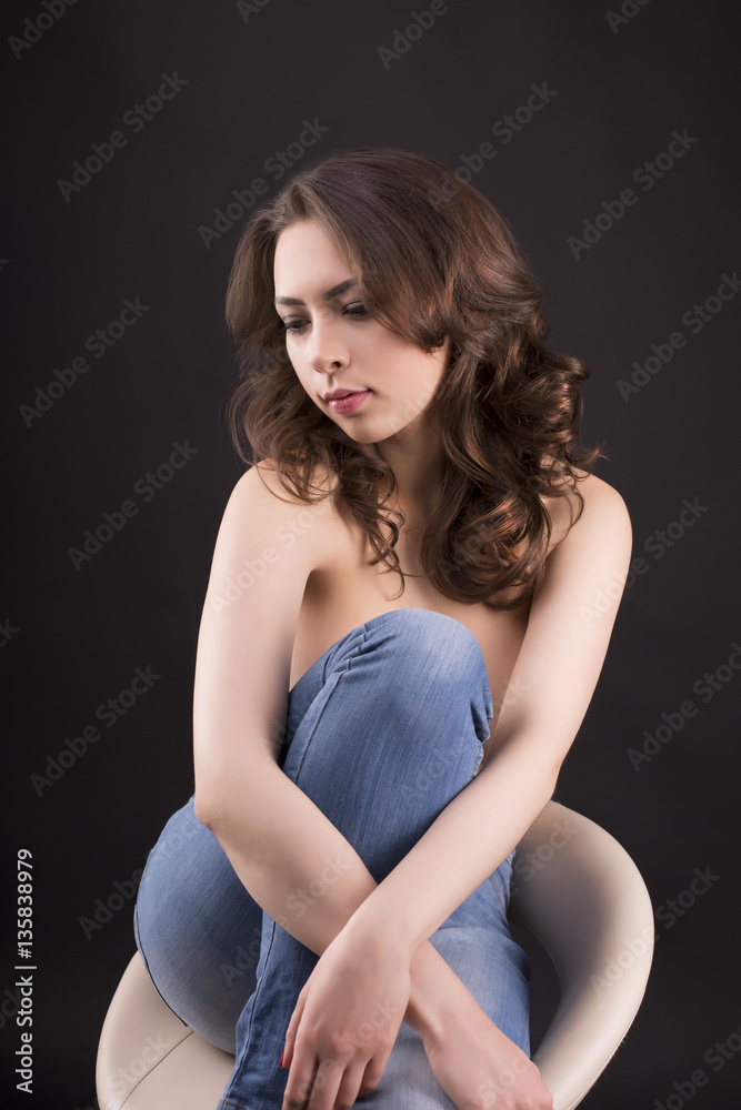 Lovely topless woman in blue jeans sitting on a chair Lovely topless woman in blue jeans sitting on a chair