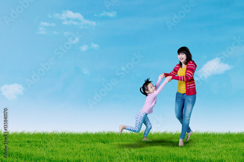 Mother and little girl playing on meadow