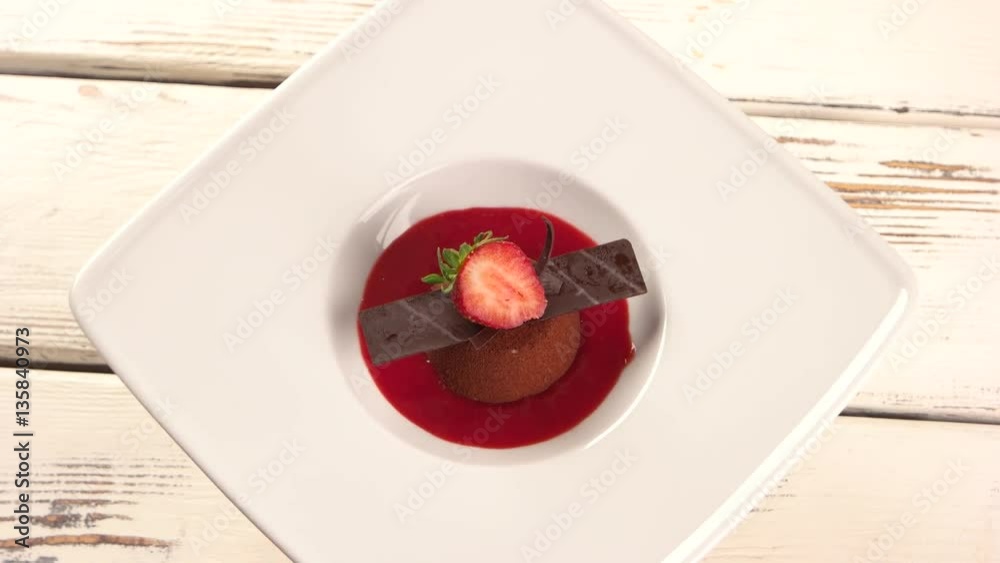 Small chocolate cake with berry. Plate with dessert is rotating. Small chocolate cake with berry. Plate with dessert is rotating.