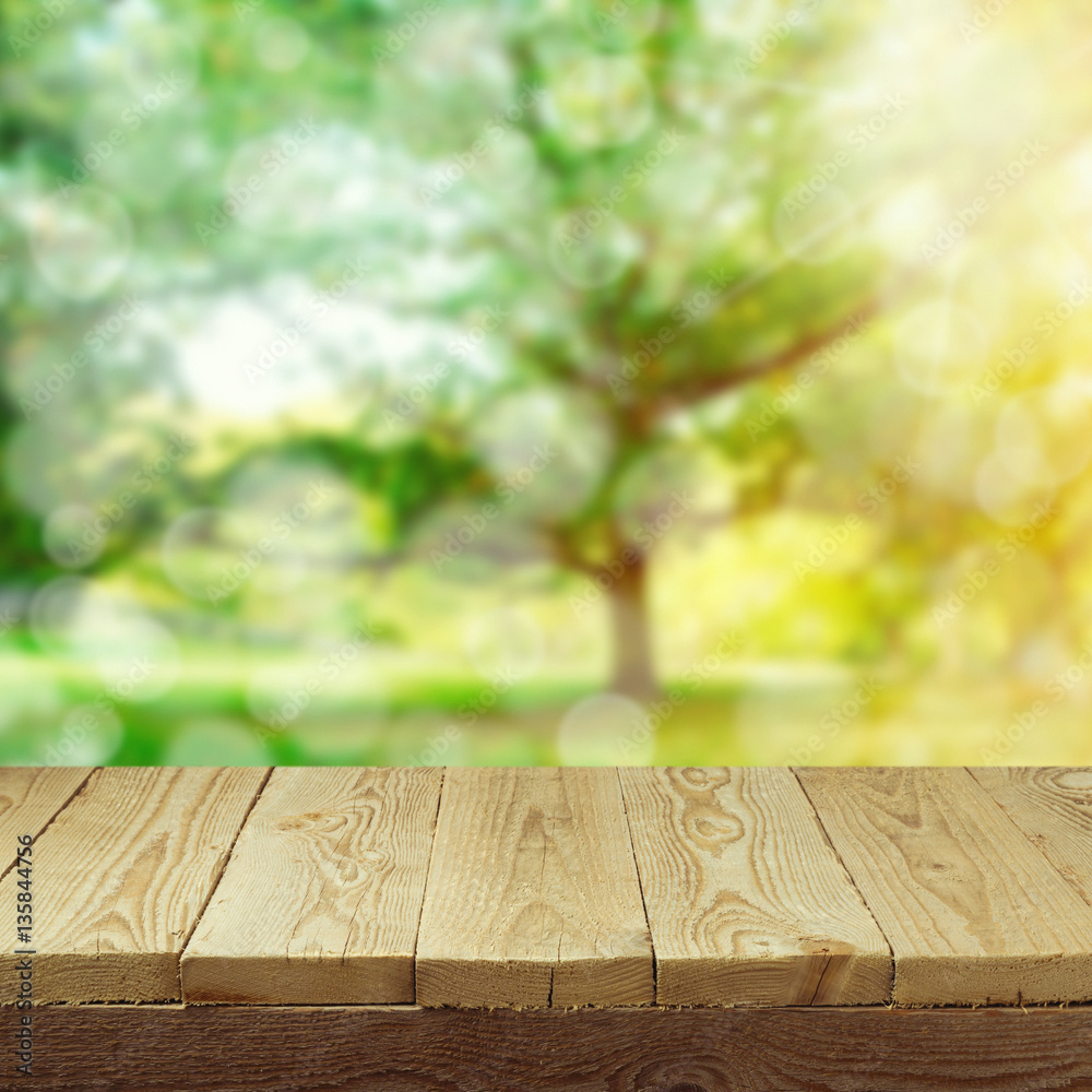 Empty wooden deck table with foliage bokeh background for product display montage. Spring or summer concept Empty wooden deck table with foliage bokeh background for product display montage. Spring or summer concept