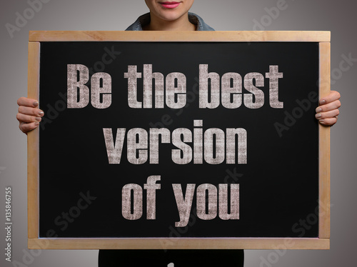 Girl (manager, student, businesswoman) in casual clothes holding a black chalk board with the text Be the best version of you photo