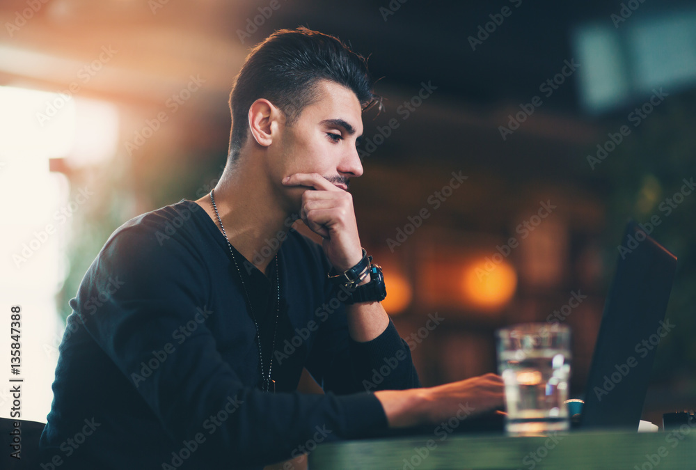 Young man working on laptop while sitting at cafe