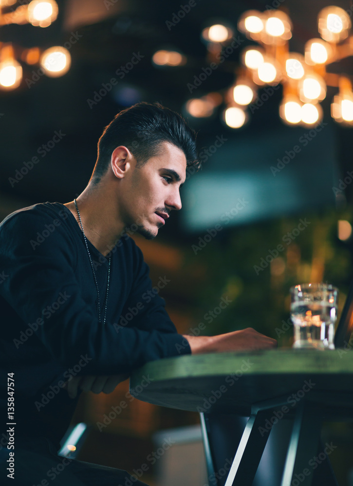 Young man working on laptop while sitting at cafe