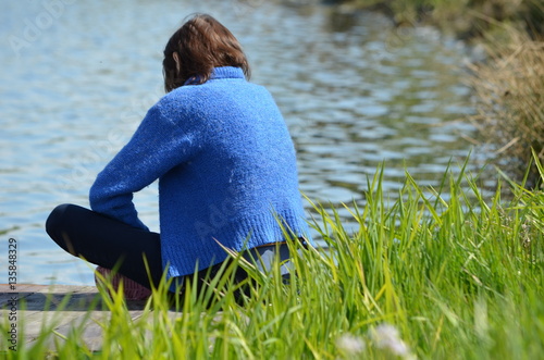 Młoda kobieta zamyślona nad brzegiem stawu/A young woman sitting pensive by the pond