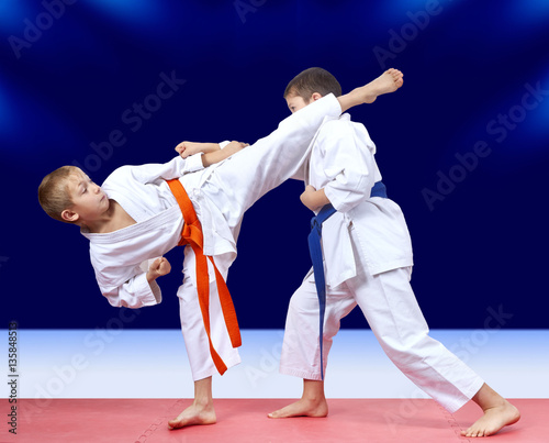 In karategi boys are training kick arm and leg towards each other