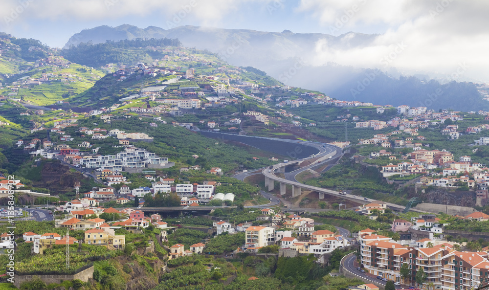 typical landscape on Madeira island, houses on hills and road background, Portugal