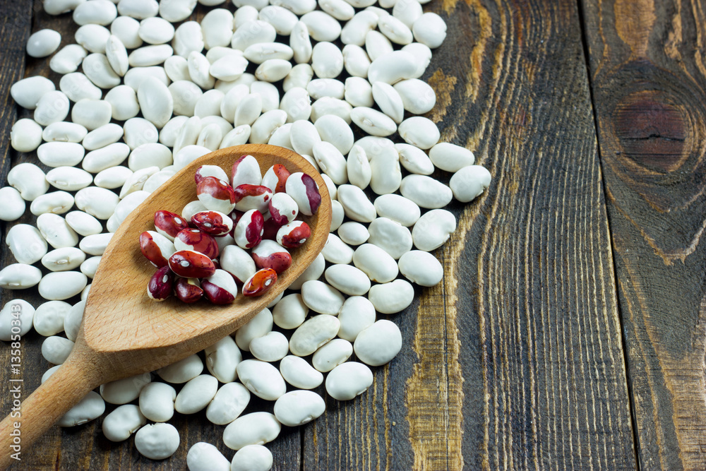white beans on a wooden table and wooden spoon