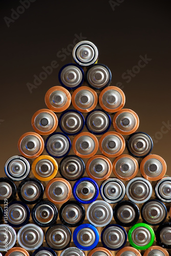 Many different colored AA batteries arranged in a pyramid on a dark gradient background 