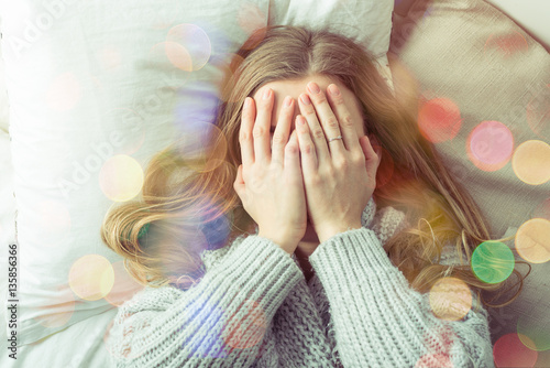 Woman hiding face with hands in bed. photo