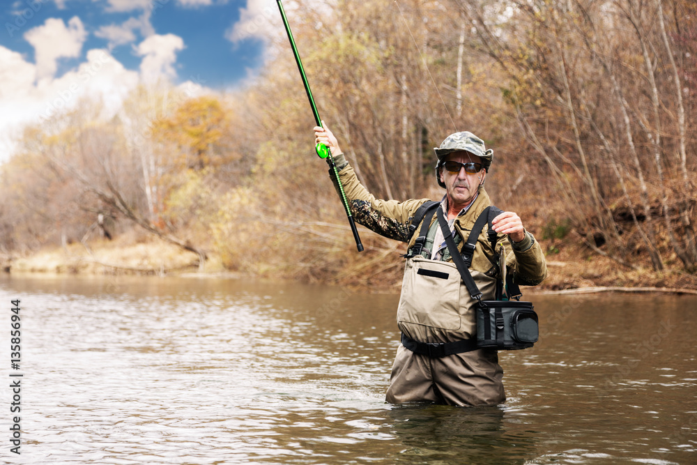 Fisherman holding a grayling caught in river Fisherman holding a grayling caught in river