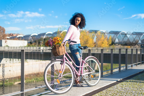 Black young woman riding a vintage bicycle