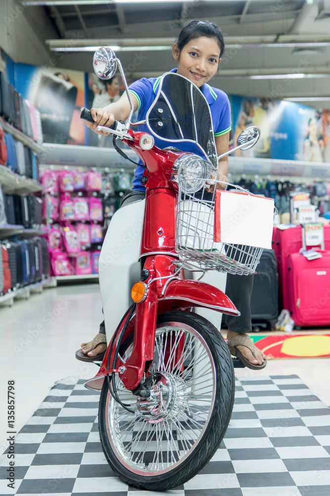 Fototapeta premium Asian woman sits on a motorcycle in the shop