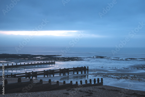 Cold Winter beach sunrise landscape at low tide with dramatic sk