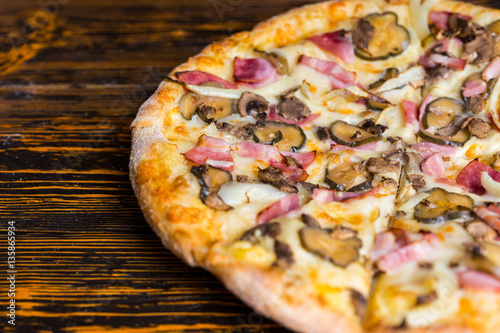 Pizza with ham, mushrooms, onion and pickles on wooden table