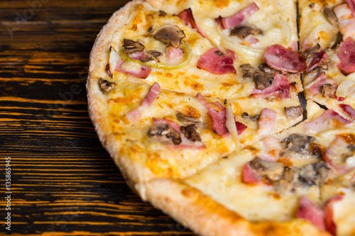 Close up of tasty pizza with ham, mushrooms and onion